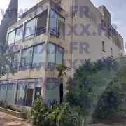 Façade du bâtiment à rénover avec larges ouvertures vitrées. 04.2026