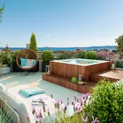 Espace extérieur en toiture avec jacuzzi, végétation et mobilier détente.