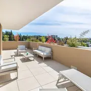 Terrasse spacieuse équipée d’un salon d’extérieur contemporain, offrant une perspective dégagée vers le quartier.