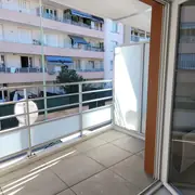 Balcon carrelé avec garde-corps en aluminium, vue urbaine dégagée sur quartier résidentiel.