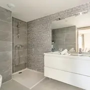 Salle de bains avec faïence contemporaine, meuble vasque, miroir et douche.