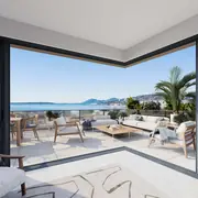 Séjour contemporain ouvert sur une terrasse offrant une vue dégagée sur la mer Méditerranée.
